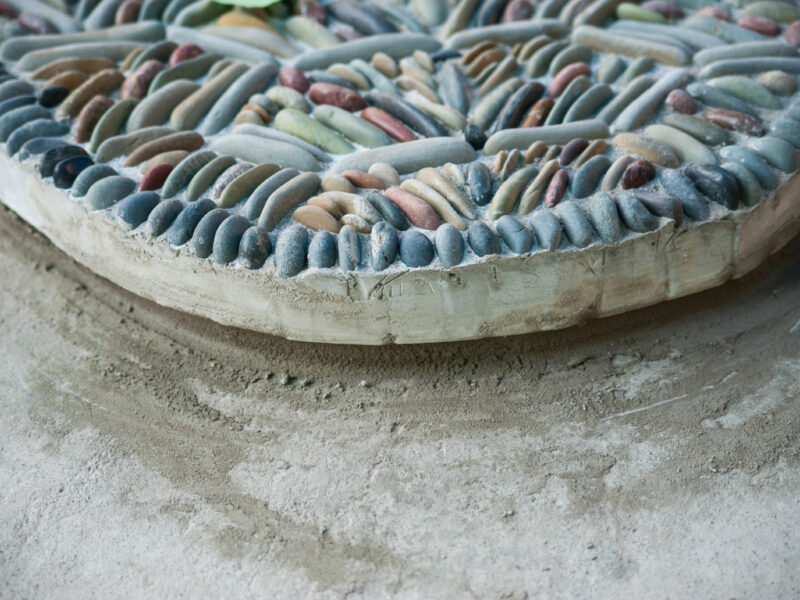 Close-up photo of half of a pebble mosaic on a concrete surface.