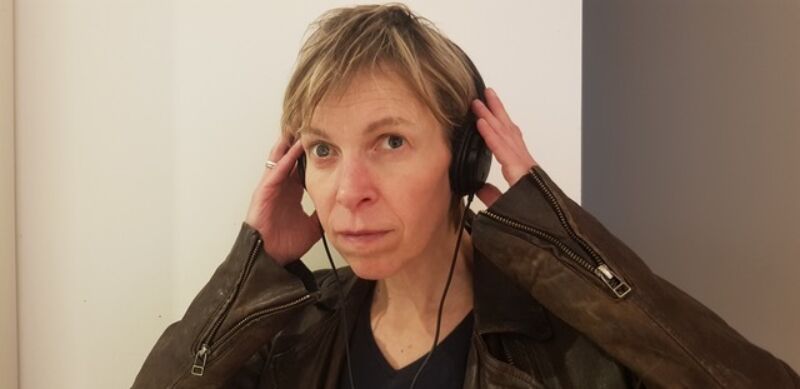 headshot of a person holding headphones to their ears