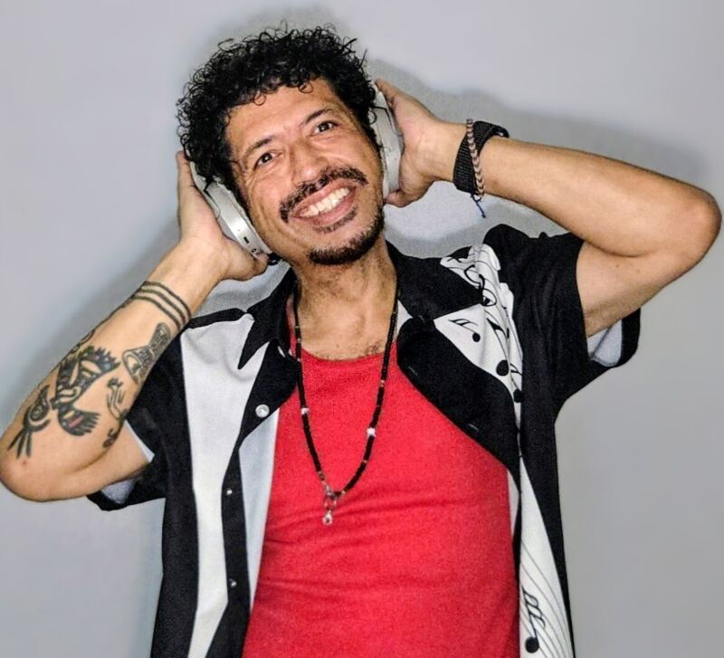 Headshot of a smiling person holding headphones to their ears