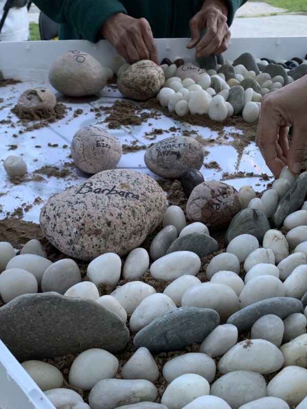 Close-up of people creating a pebble mosaic.