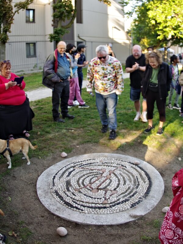A large group of people celebrate the unveiling of a pebble mosaic.