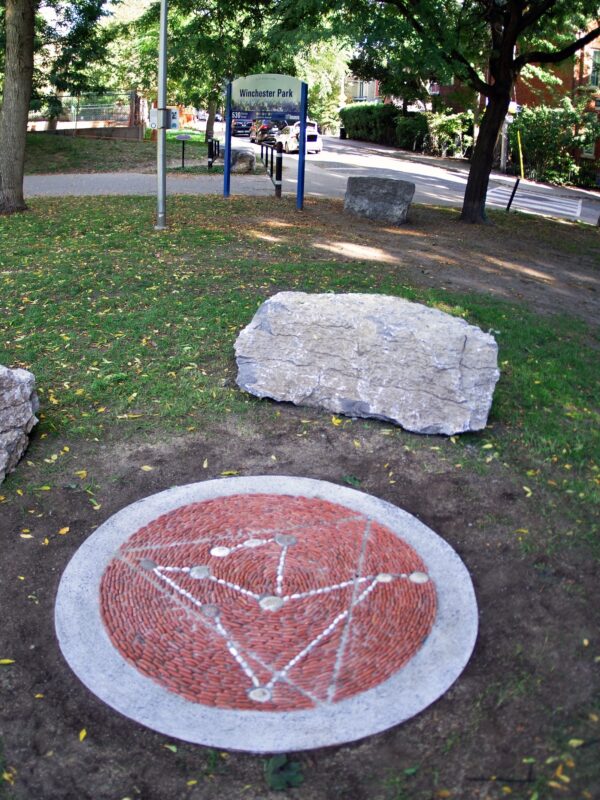 A pebble mosaic in a park surrounded by stone seating.