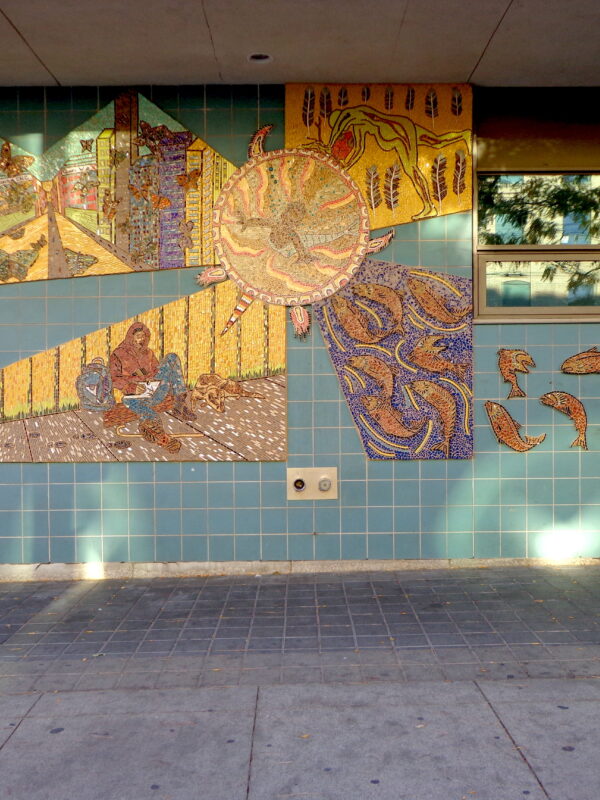 A large colourful mosaic installed on an exterior tiled wall.