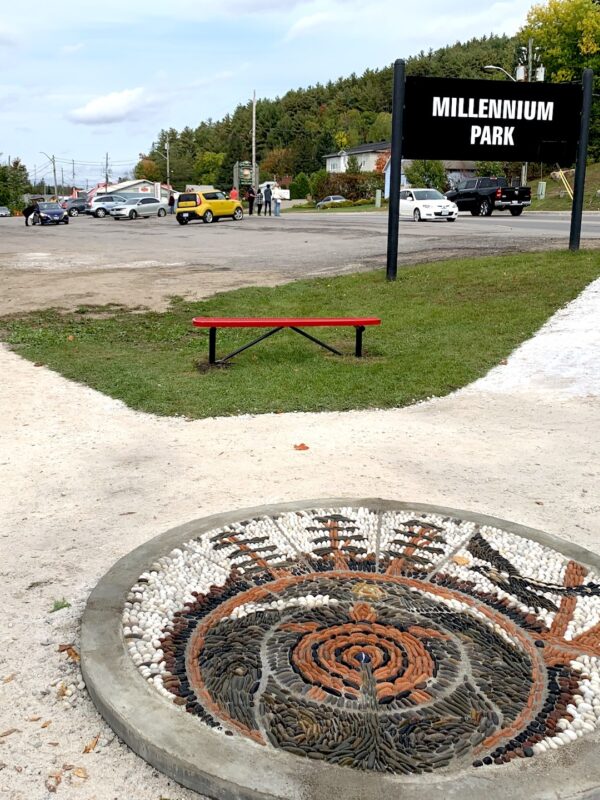 Photo of pebble mosaic by park sign that reads “Millenium Park”.