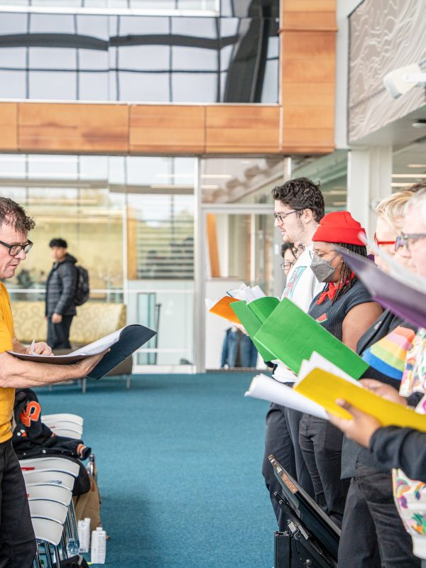 A choir stands together singing out to the audience.