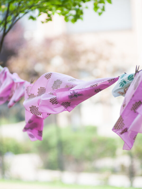 Napkins hand printed with bumblebee and bee hive motif hang to dry on a clothesline.