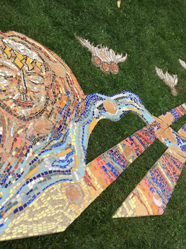 A large mosaic sitting on grass waiting to be installed.